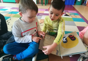 Dwóch chłopców z przedszkola z Radomia siedzą na dywanie z książeczką