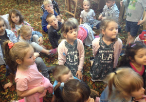 Dzieci siedzą na dywanie w bibliotece i słuchają bajki