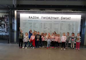 Zdjęcie grupowe dzieci z grupy Kangurków, w tle napis: Razem tworzymy swiat
