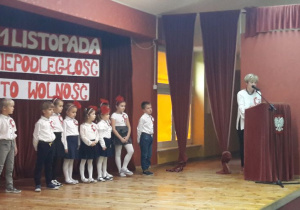 Dzieci oraz Pani Dyrektor na scenie, w tle napis: 11 listopada, niepodległość to wolność