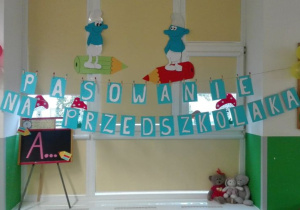 Dekoracja Smerfów, napis: Pasowanie na przedszkolaka, nad nim dwa smerfy na ołówkach