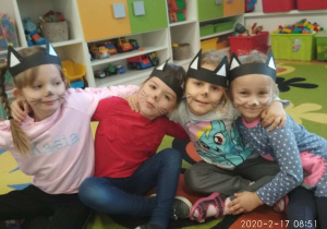 Dziewczynki w przebraniach kotów, siedzą na dywanie