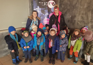 Zdjęcie grupowe Jabłuszek ze swoimi nauczycielkami, w tle plakat Teatru V6