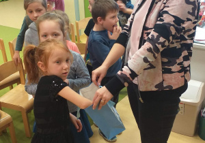Dzieci losują swój przyszły zawód z torby, którą trzyma nauczycielka
