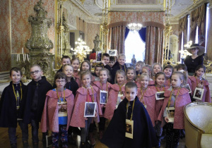 Dzieci z grupy Koty we wnętrzach Pałacu Herbsta ubrane w ozdobne peleryny: różowe - dziewczynki, granatowe - chłopcy