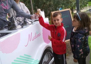 Sówki przy samochodzei z lodami, chłopiec sięga po loda