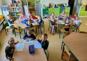 Dzieci wykonują pracę plastyczną przy stoliku