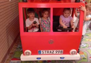 Dzieci w zabawkowym wozie strażackim
