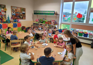 Dzieci przy stolikach malują kamienie