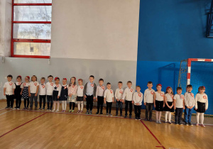 Dzieci z grupy Lisków na galowo z kotylionami stoją na auli