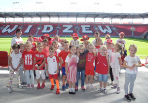 Zdjęcie grupowe dzieci z grupy Kotów, w tle napis Widzew