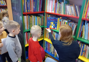 Dzieci oglądają książki na regałach w bibliotece