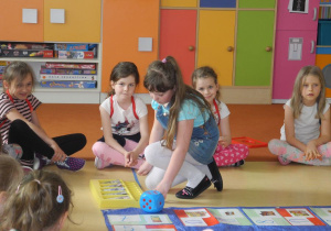 Dzieci podczas warsztatów, dziewczynka wykonuje rzut kostką
