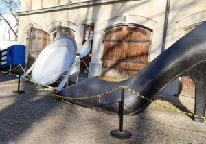 Ogromny but damski, talerz i sztućce oraz telefon przed Muzeum