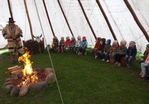 Przedszkolaki w tipi przy ognisku z Indianinem