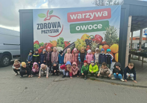 Dzieci na tle banera z warzywami i owocami
