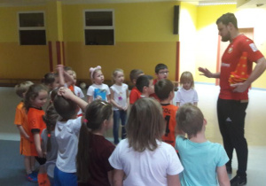 Pan Michał opowiada o czekającym dzieci następnym zadaniu, dzieci stoją wokół niego i słuchają