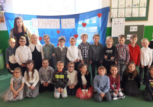 Zdjęcie grupowe Żabek wraz z Panią, w tle napis na niebieskim tle napis: Kochamy Was