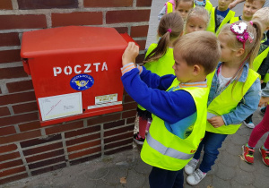 Chłopiec wrzuca kartki do skrzynki pocztowej