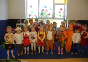 Zdjęcie grupowe Kotków na tle okna przystrojonego w kolorowe, jesienne liście