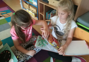 Dwie dziewczynki z przedszkola z Radomia sidzą na dywanie z książeczką