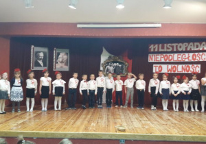 Grupa Krasnoludków na scenie, w tle dekoracja niepodległościowa