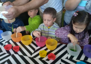 Dzieci podczas robienia mydełek, mieszają barwnik w miseczkach