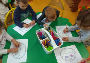 Dzieci kolorują jeże przy stoliku