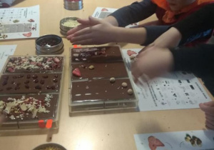 Dzieci podczs warsztatów, dekorują swoje czekolady