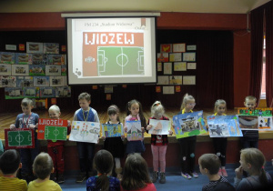 Dzieci prezentują prace, na tablicy interaktywnej w tle rysunek przedstawiający stadion Widzewa