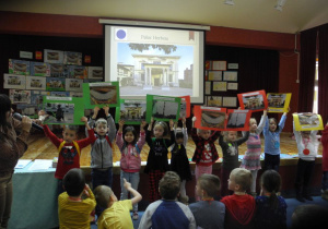 Dzieci prezentują prace, na tablicy interaktywnej w tle rysunek przedstawiający Pałac Herbsta