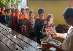 Dzieci podczas warsztatów, Pan Pszczelarz smaruje kromki chleba midem, dzieci czekają w kolejce