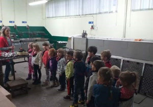 Dzieci podczas zwiedzania fabryki, słuchają Pani stojącej obok maszyny