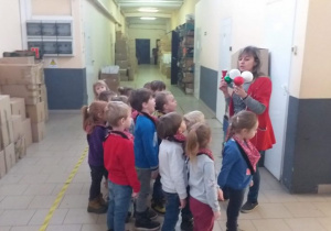 Dzieci podczas zwiedzania fabryki, oglądają bombki pokazywane przez Panią