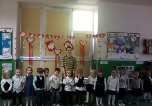 Dzieci z grupy Smerfy wraz z Panią nauczycielką gotowe do uroczystości, nad nimi napis:Kochamy Was