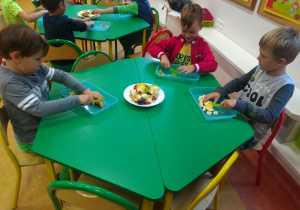 Przy stole siedzi trzech chłopców z grupy Sowy, kroją owoce na sałatkę