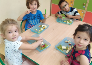 Przy stole siedzą dzieci z grupy Małpki, kroją owoce na sałatkę