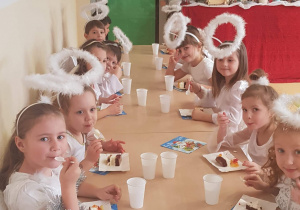 Dzieci z grupy Jabłuszka siedzą przy stołach, jedzą ciasto