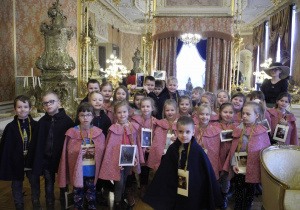 Dzieci z grupy Koty we wnętrzach Pałacu Herbsta ubrane w ozdobne peleryny: różowe - dziewczynki, granatowe - chłopcy
