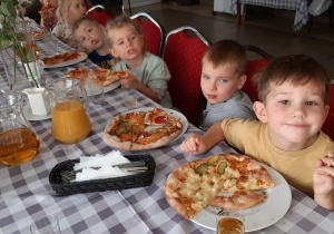 Dzieci jedzą zrobioną przez siebie pizzę