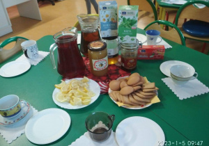 Stół z poczęstunkiem: herbaty, miody, herbatniki, filiżanki
