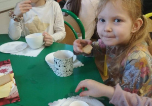 Dziewczynki piją herbatkę i jedzą herbatniki