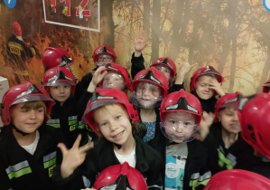 Dzieci w nakryciach głowy i kurtkach strażackich