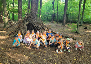 Dzieci na tle szałasu obok drzewa