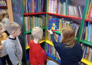 Dzieci oglądają książki na regałach w bibliotece