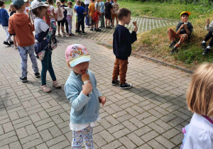 Dzieci jedzą lody, w tle szaleństwa na dmuchańcach