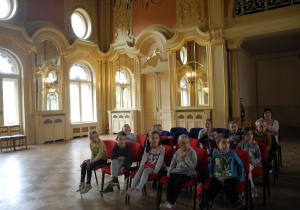 Dzieci siedzą na fotelach w pałacu