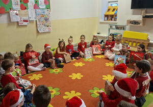 Dzieci siedzą na dywanie z prezentami