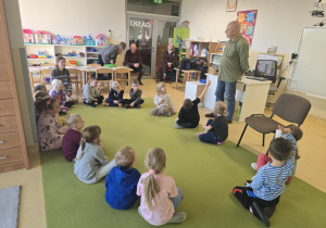 Dzieci słuchają siedząc na dywanie