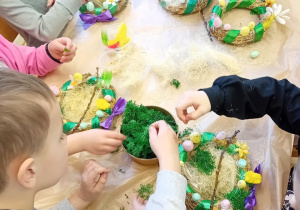 Dzieci ozdabiają wianki mchem